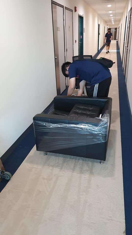 man wrapping sofa in hallway