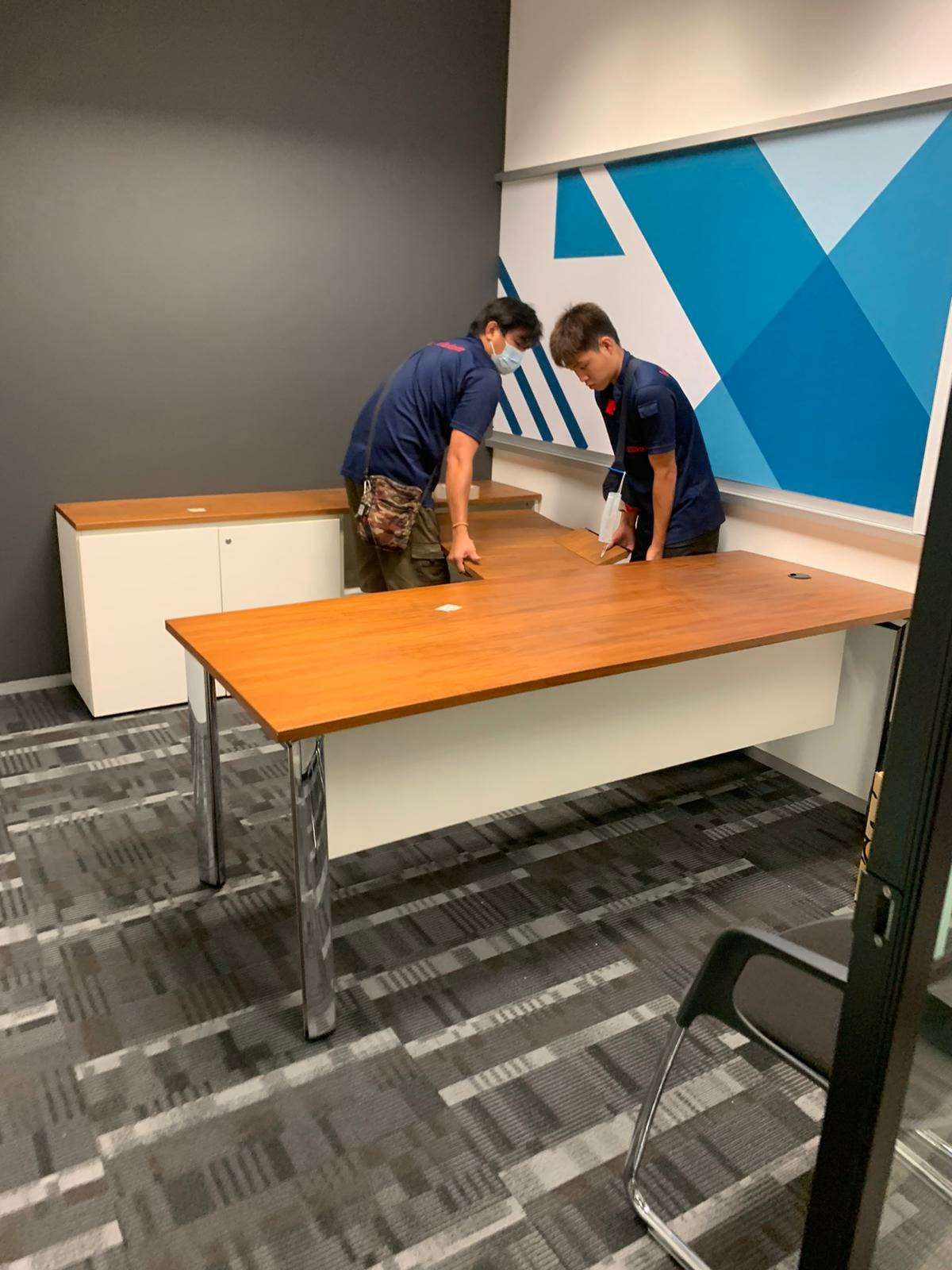 two men moving and adjusting office table