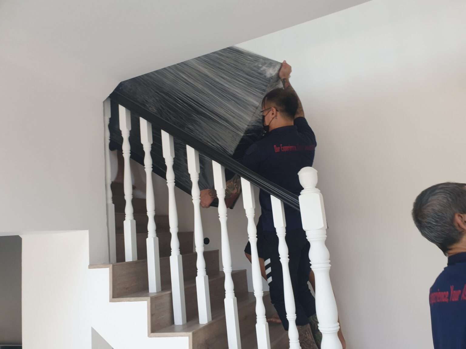 home mover staff moving up the stairs while holding a black piece of furniture